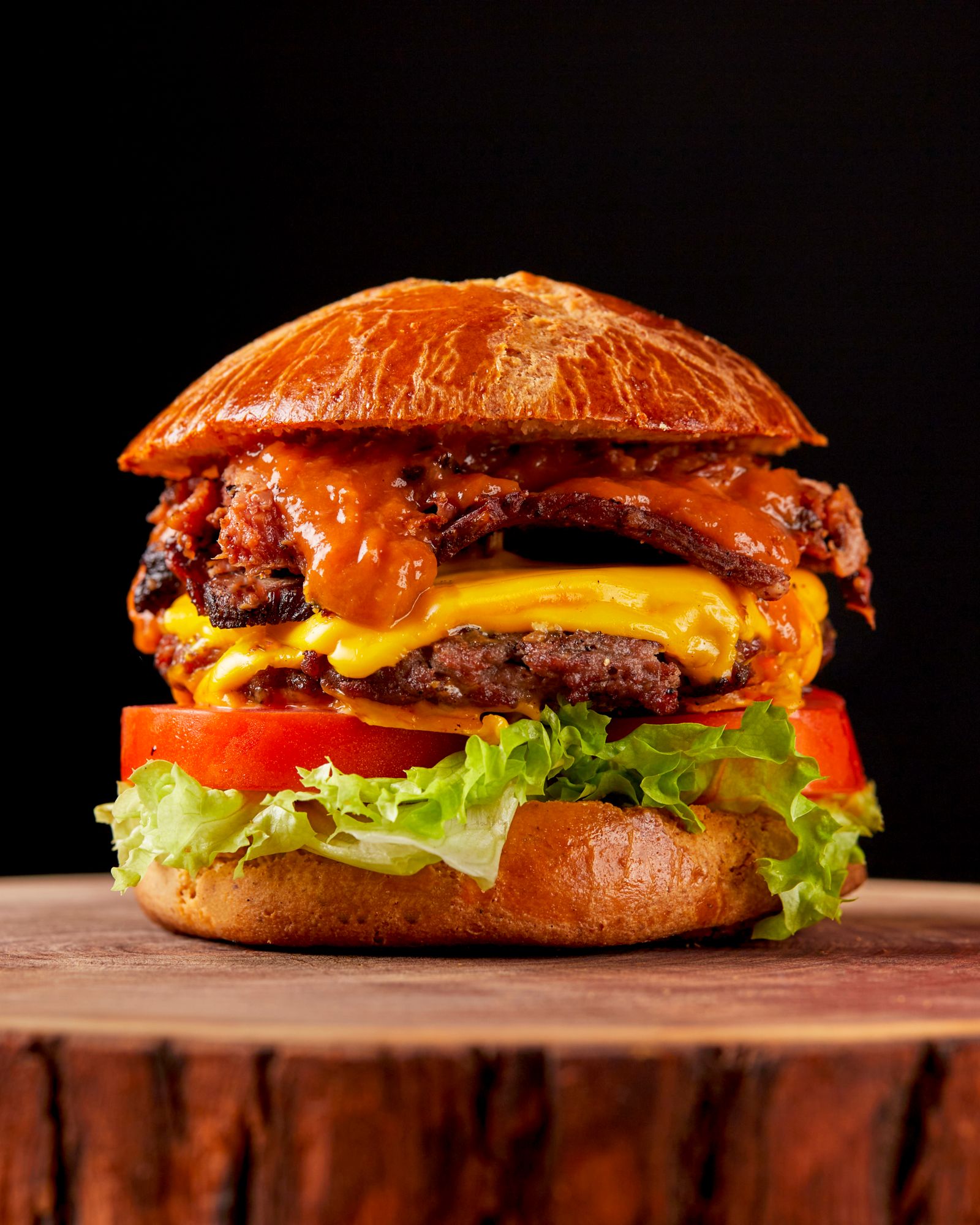 a stacked cheeseburger on a dark wood table.