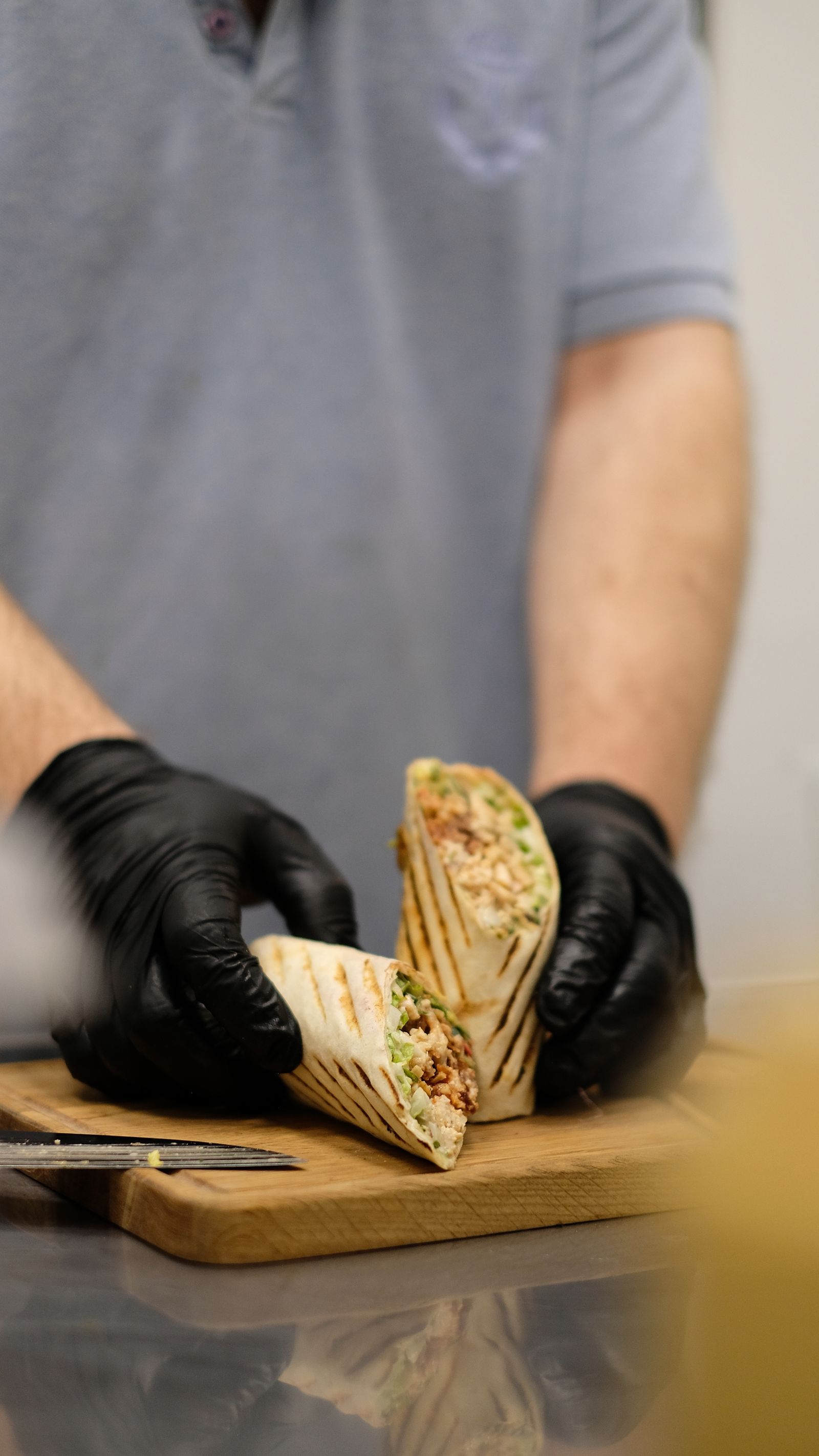 hands preparing a grilled wrap on a cutting board.