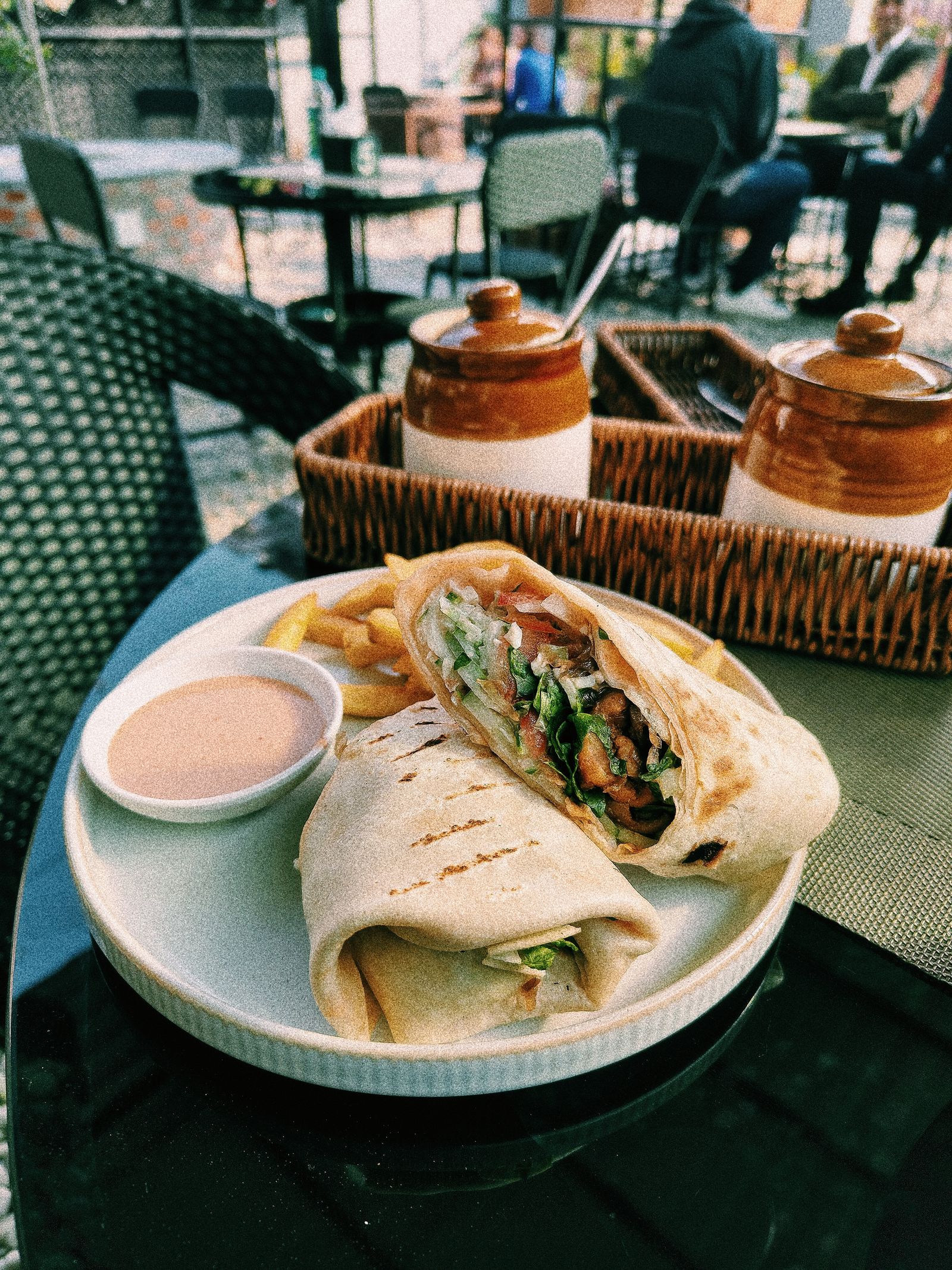 a grilled wrap with fries on a casual table.